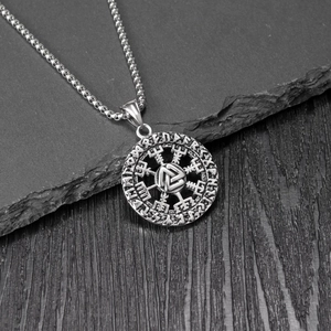 Close-up of vintage Nordic rune pendant with Valknut symbol on dark rock background