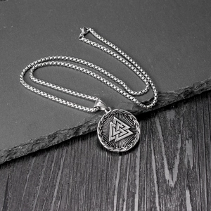 Détail du pendentif Valknut sur une chaîne carrée argentée sur une plaque de pierre