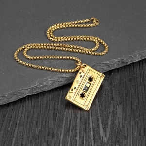 Retro gold cassette tape pendant necklace with a beaded chain on a dark textured background