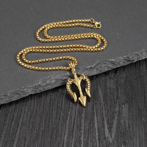 Vintage golden trident pendant necklace in stainless steel on a stone and wood surface