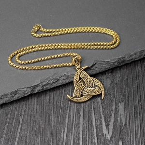 Detailed macro shot of a golden Viking Odin triple horn pendant with Celtic knotwork
