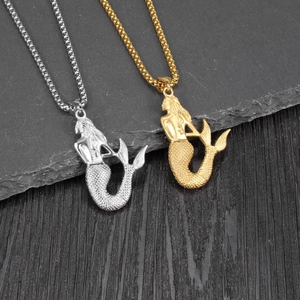 Golden and silver mermaid pendant necklaces with bead chains on dark stone background
