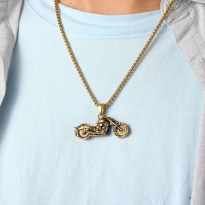 Close-up of retro gold motorcycle pendant with box chain on a male model's outfit