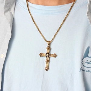 Close-up of a gold Celtic cross necklace with a black skull relief on a male model
