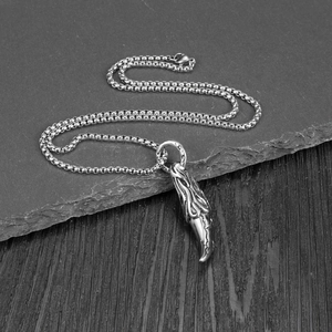 Detail shot of vintage wolf tooth pendant with tribal patterns on grey slate background