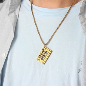 Close-up of retro gold cassette pendant with detailed texture on a golden bead chain