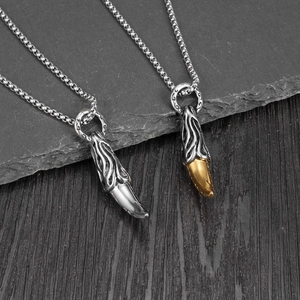 Close-up of punk wolf tooth pendants with flame textures in silver and gold finishes