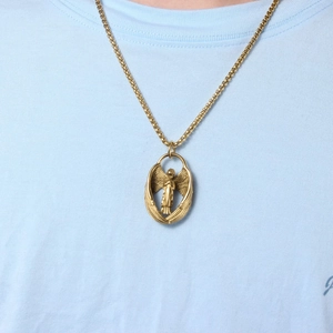 Detailaufnahme eines goldenen Engelsflügel-Anhängers mit aufwendigem Engel-Reliefdesign