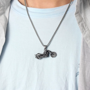 Detail of vintage motorcycle pendant with textured metal chain on casual outfit