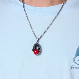 Gros plan du pendentif griffe de dragon avec pierre rouge sur chaîne en acier inoxydable