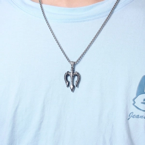 Close-up of a vintage stainless steel trident pendant necklace on a cotton t-shirt