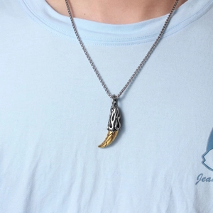 Detail of retro wolf tooth pendant with silver flame texture and gold-tone box chain
