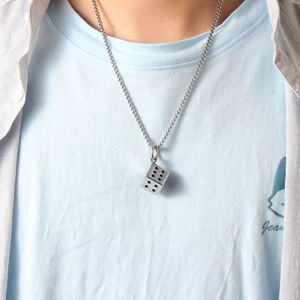 Dettaglio della collana con ciondolo a dado argento indossata da un modello uomo