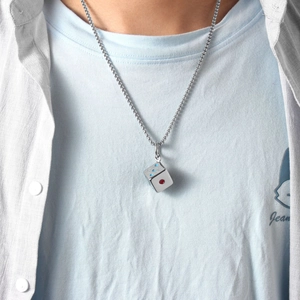 Primo piano di una collana con ciondolo a dado d'argento e punti smaltati su un modello