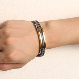Gros plan sur un bracelet noir en silicone avec plaque dorée et bordure en maille