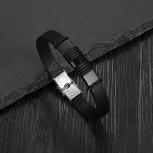 Close-up of black PU leather bracelet showing stainless steel clasp with engraved logo