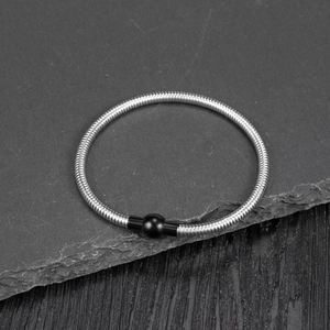 Detailed macro of silver spring steel bracelet with black magnetic beads on stone