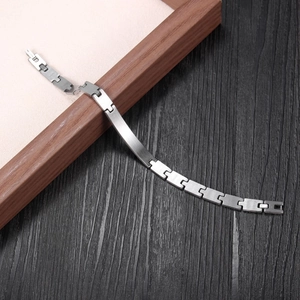 Detail of brushed stainless steel curved bar bracelet on dark wood background