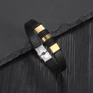 Detail of stainless steel clasp and gold metal plates on black braided leather bracelet