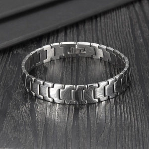 Macro shot of silver-gray stainless steel bracelet with industrial brushed wave texture