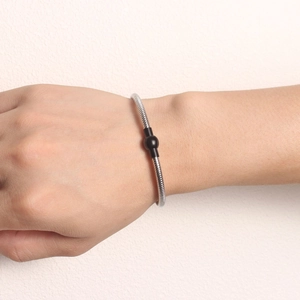 Close-up of silver snake bone chain bracelet with black magnetic sphere clasp on wrist