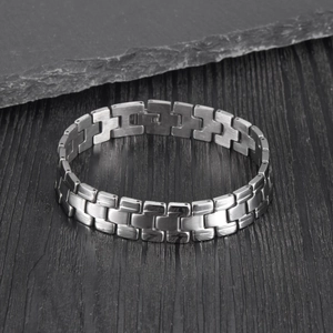 Gros plan d'un bracelet gourmette en acier inoxydable brossé style montre sur fond en bois