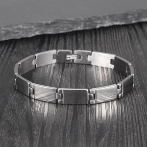 Bracelet chaîne en acier inoxydable brossé pour femme sur un fond en bois foncé élégant