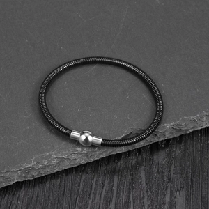 Detail of black snake chain bracelet featuring a polished silver magnetic sphere clasp