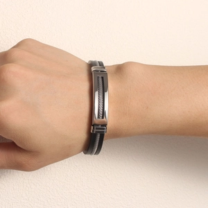 Detail of a black silicone bracelet with a snake-scale mesh steel plate on a male wrist