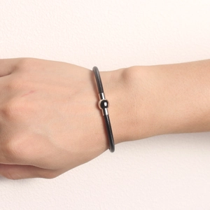 Detail of black spiral spring bracelet with silver magnetic ball on wrist