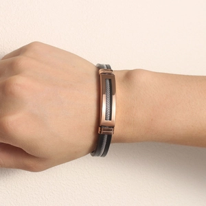 Detail of black silicone wristband featuring rose gold plate and silver mesh texture