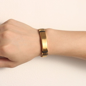 Detail of adjustable gold Milanese mesh bracelet with polished curved bar and black rings