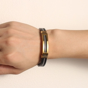 Close-up of stainless steel gold plate with silver mesh on a black silicone wristband