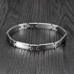 Détail du bracelet en acier inoxydable avec maillons en H et texture damassée sur bois