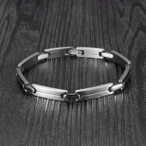 Detailed view of stainless steel bracelet with brushed finish on dark wood surface