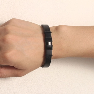 Close-up of a minimalist black PU leather bracelet with a polished black metal buckle
