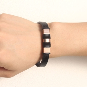 Close-up of black PU leather bracelet with rose gold metal parts and rubber rings