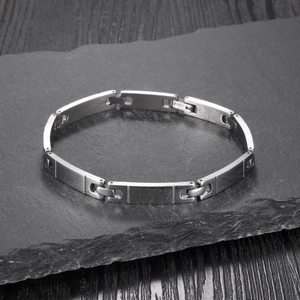 Macro view of silver stainless steel link bracelet with S.STEEL stamp on gray rock