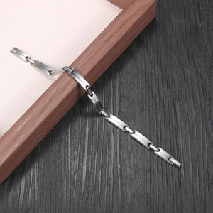 Minimalist silver stainless steel link bracelet with industrial matte finish on wood base