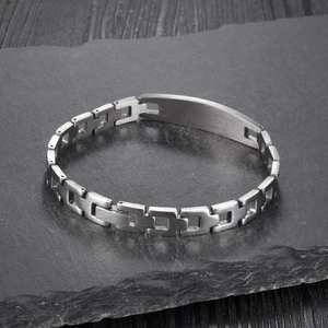Détail d'un bracelet à maillons en acier inoxydable poli sur fond de pierre foncée