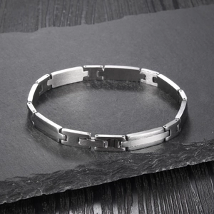 Détail du bracelet en acier industriel avec maillons en H sur fond de pierre