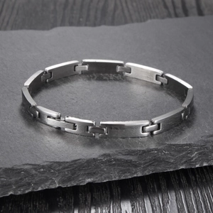 Close-up of brushed stainless steel bracelet showing H-link structure on stone background