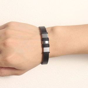 Close-up of black leather bracelet with silver metal cubes and rubber rings on wrist