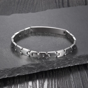 Macro shot of silver stainless steel chain bracelet with a brushed metal plate on rock