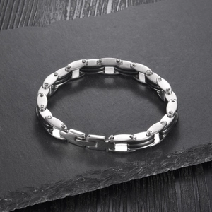 Industrial style stainless steel link bracelet with rivets on dark stone surface