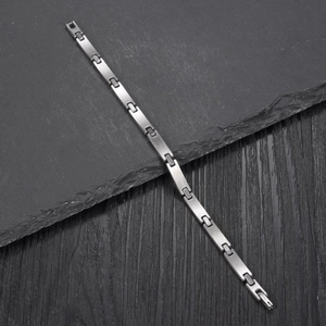 Minimalist stainless steel chain bracelet for men with brushed silver finish on a stone background