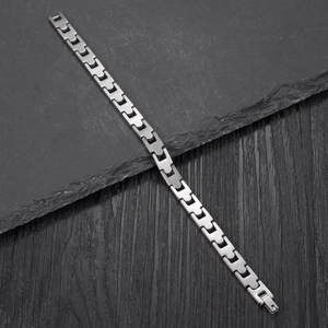 Minimalist silver stainless steel H-link bracelet with fold-over clasp on wooden background