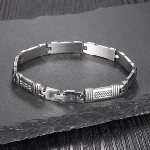 Détail d'un bracelet en acier inoxydable mat avec maillons rayés sur pierre sombre