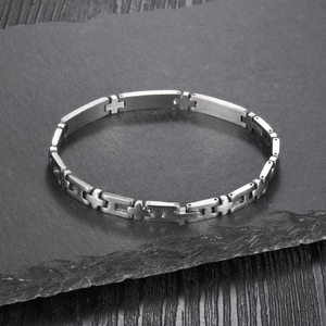 Macro detail of silver stainless steel bracelet featuring refined cross-shaped link connectors