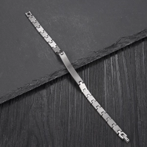Polished stainless steel ID link bracelet for women on dark stone and wood background